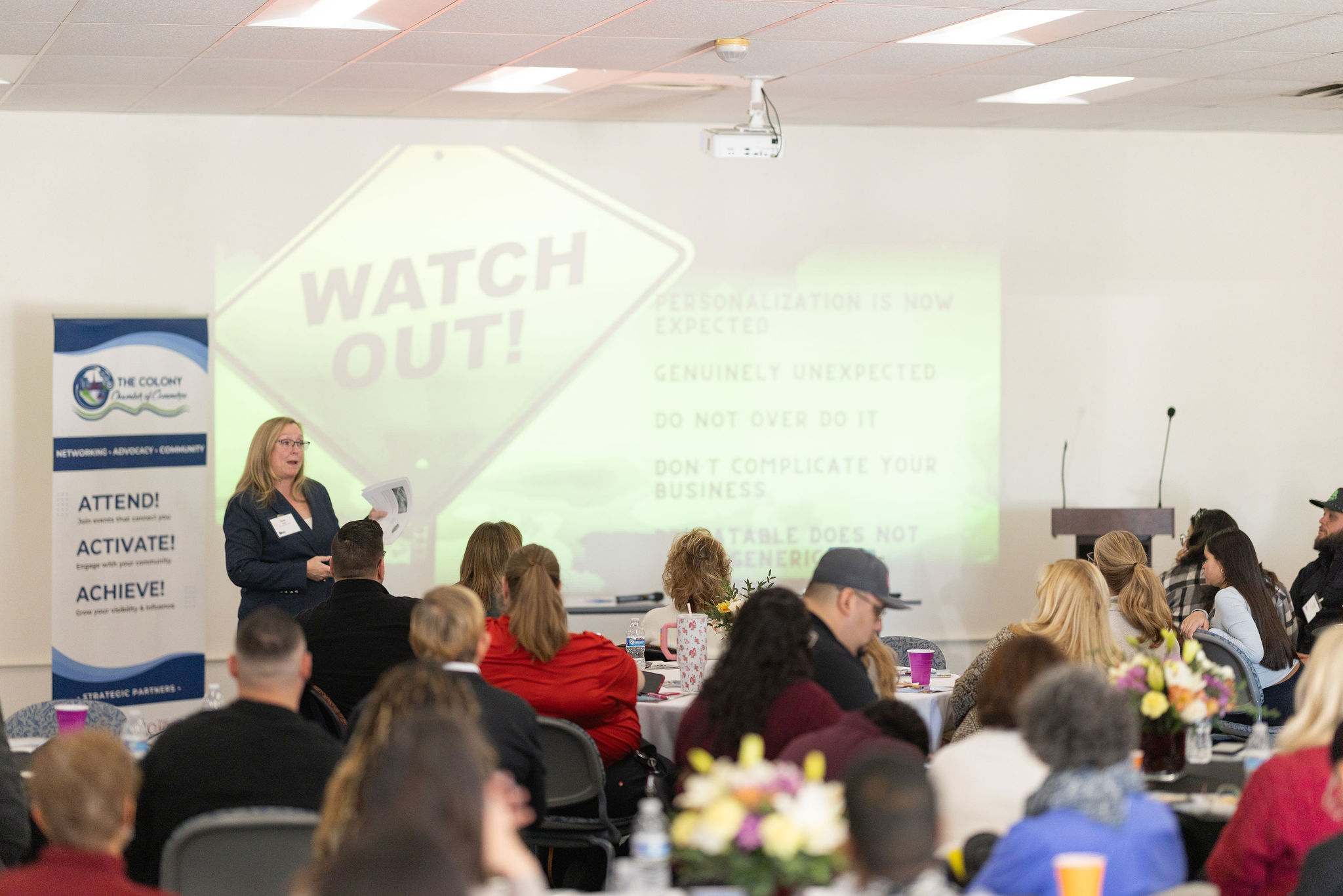 Paula Ward, professional photographer and guest speaker, presents at the 2026 Leadership Lunch hosted by The Colony Chamber of Commerce, speaking to a seated audience about creating memorable customer experiences.